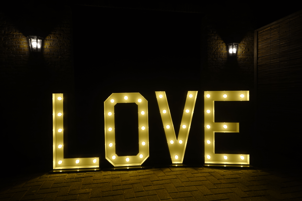 Grote LOVE-lichtletters buiten op een feestlocatie in de avond