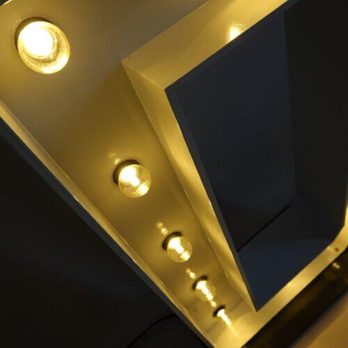 Close-up van warmwitte lampen en de gouden rand van handgemaakte lichtletters